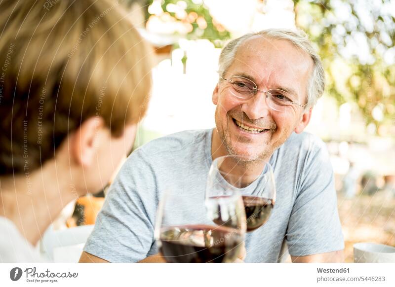 Smiling senior couple clinking red wine glasses outdoors twosomes partnership couples Wine smiling smile people persons human being humans human beings Alcohol