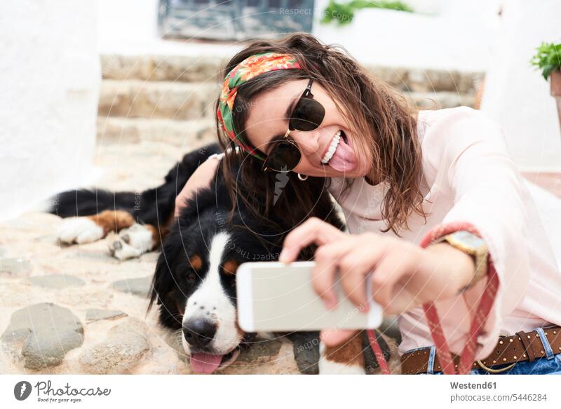 Brunette girl taking selfie, tired bernese mountain dog lying on the floor dogs Canine woman females women leisure free time leisure time Smartphone iPhone