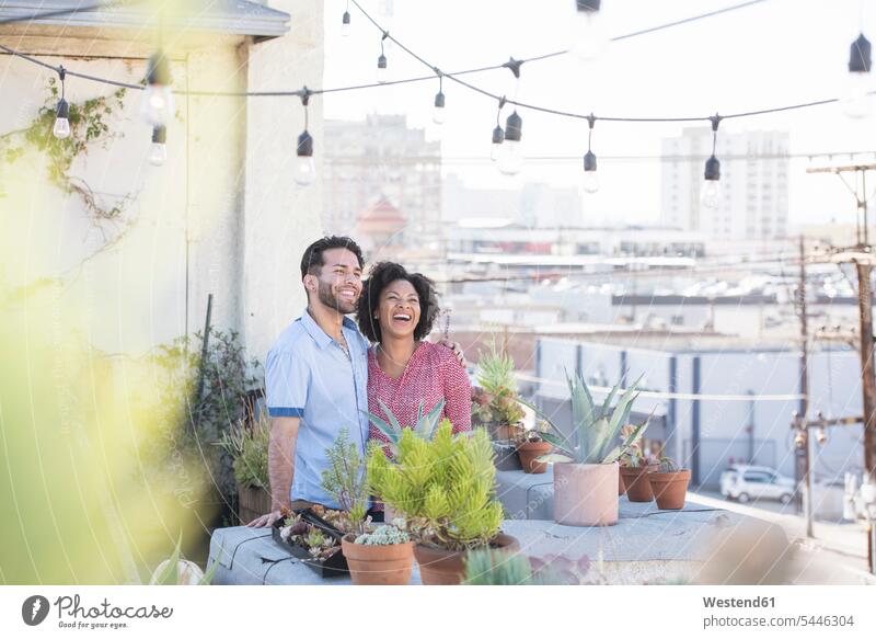 Couple standing in their rooftop garden roof garden hanging garden gardening yardwork yard work roof terrace deck happiness happy couple twosomes partnership