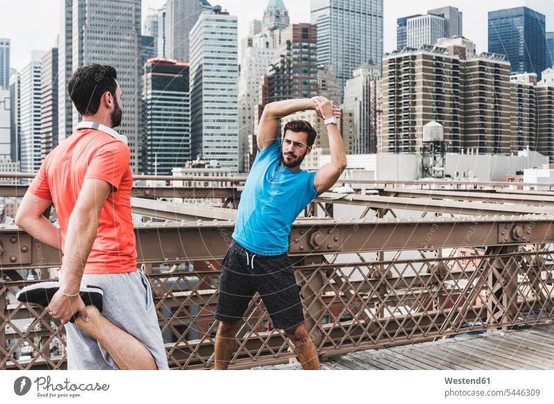 USA, New York City, two athletes stretching on Brooklyn Brige Jogging friends man men males bridge bridges fitness sport sports friendship Adults grown-ups