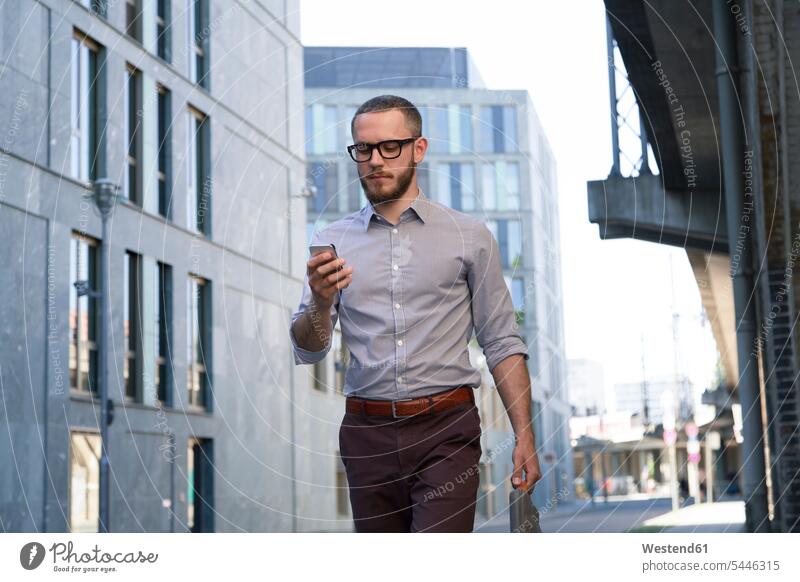 Businessman looking at cell phone in the city Business man Businessmen Business men mobile phone mobiles mobile phones Cellphone cell phones business people