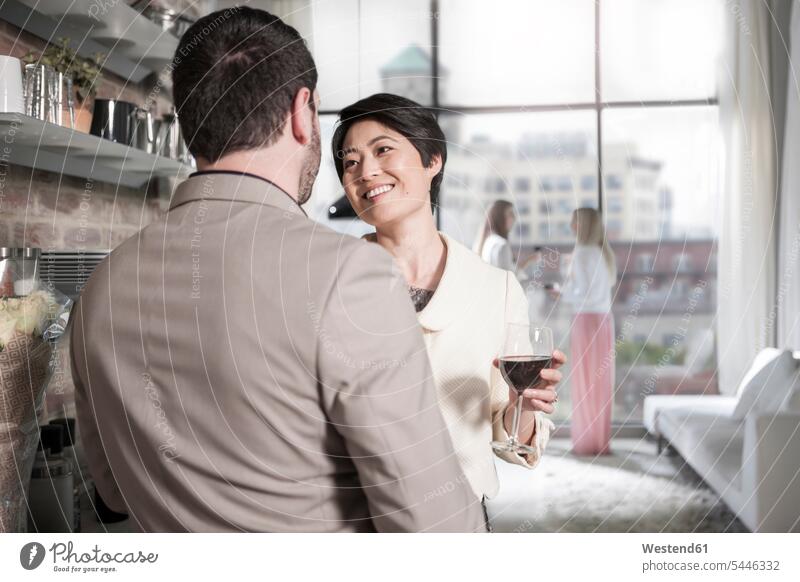Man and woman with red wine glass socializing in a city apartment celebrating celebrate partying socialise socialising socialize home at home smiling smile