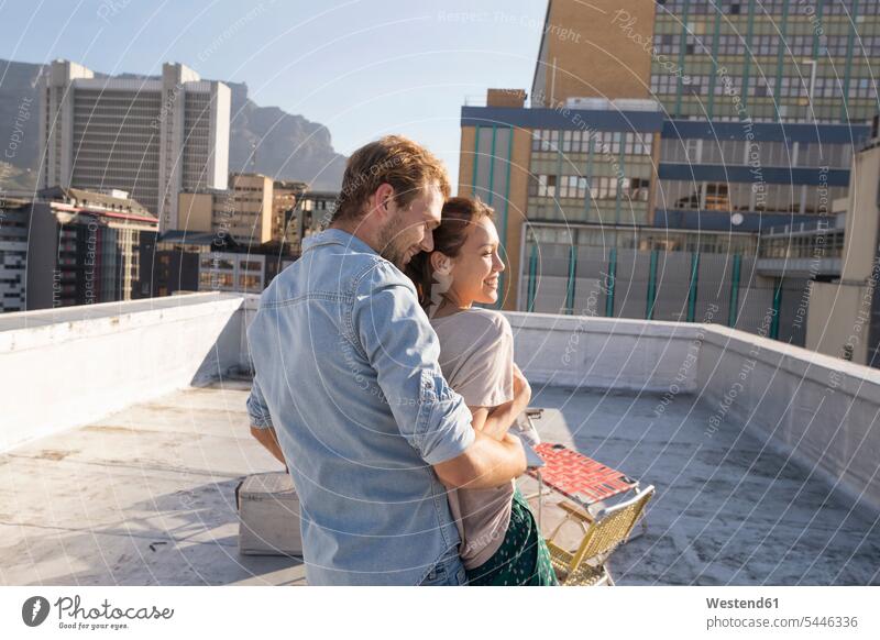 Young couple celebrating on a rooftop terrace, embracing at sunset Mixed Race Person mixed-race Person mixed race ethnicity leisure free time leisure time