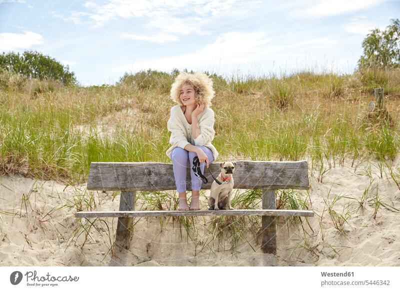 Portrait of happy young woman sitting on bench in the dunes with her dog females women dogs Canine Adults grown-ups grownups adult people persons human being