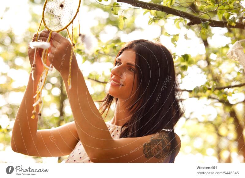 Woman hanging dream catcher on branch of a tree smiling smile Tree Trees dreamcatcher woman females women Adults grown-ups grownups adult people persons