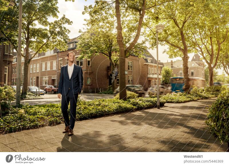 Netherlands, Venlo, confident businessman standing on pavement city town cities towns Businessman Business man Businessmen Business men smiling smile Side Walk