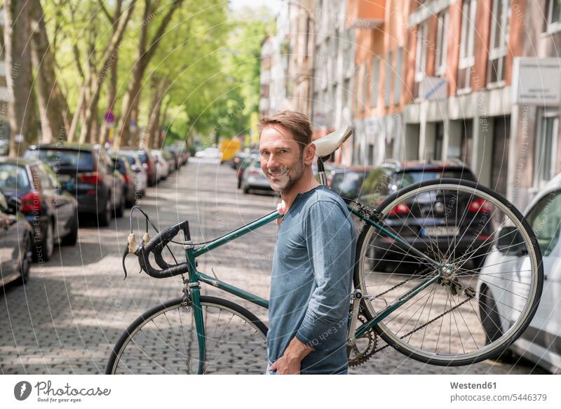 Portrait of smiling mature man carrying his bicycle on the shoulder portrait portraits bikes bicycles men males Adults grown-ups grownups adult people persons