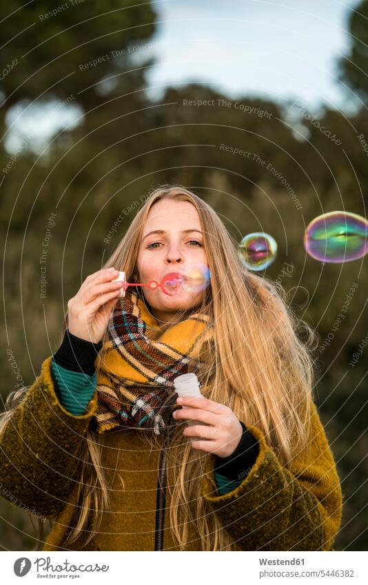 Portrait of young woman blowing soap bubbles in nature females women Adults grown-ups grownups adult people persons human being humans human beings portrait