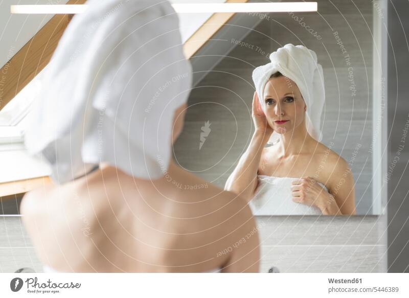 Woman looking at her mirror image in the bathroom portrait portraits Bath woman females women reflexion reflection Adults grown-ups grownups adult people