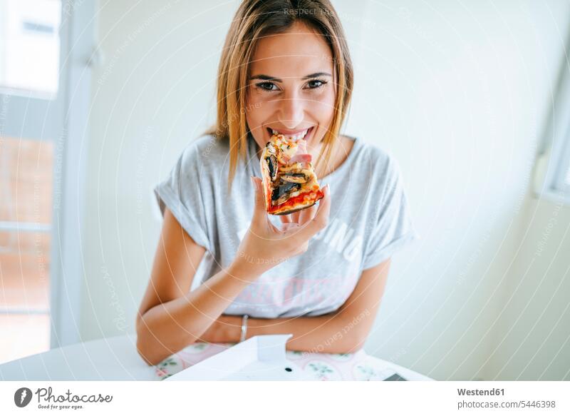 Portrait of young woman eating pizza at home females women Pizza Pizzas Adults grown-ups grownups adult people persons human being humans human beings Food