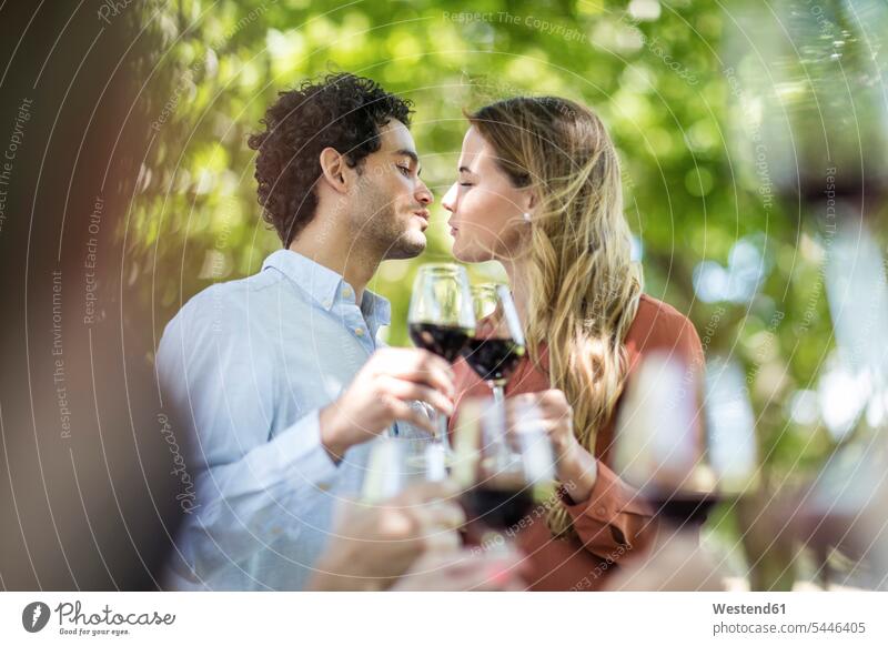 Couple kissing during lunch in garden with red wine Red Wine Red Wines celebrating celebrate partying kisses couple twosomes partnership couples Alcohol
