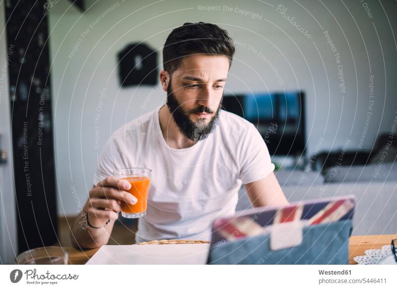 Young man having breakfast men males Glass Drinking Glasses Adults grown-ups grownups adult people persons human being humans human beings Dishes Crockery