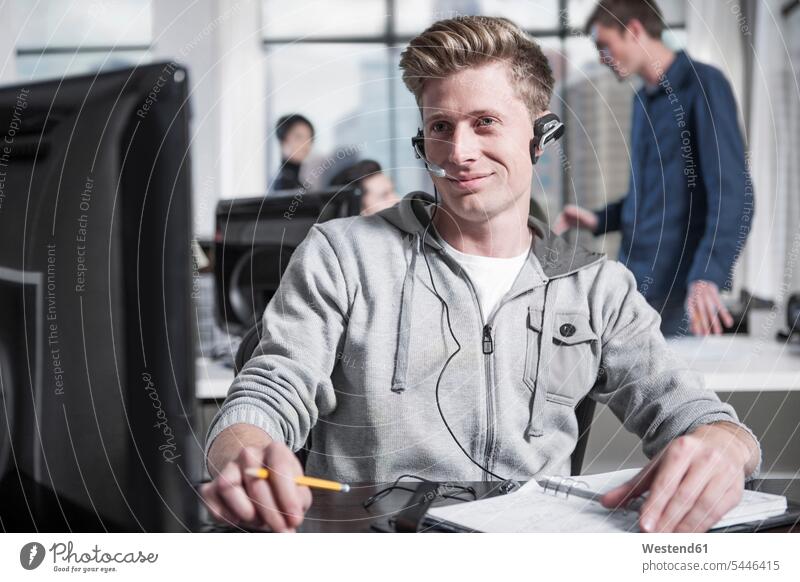 Young man at desk in office wearing a headset headsets on the phone call telephoning On The Telephone calling offices office room office rooms men males