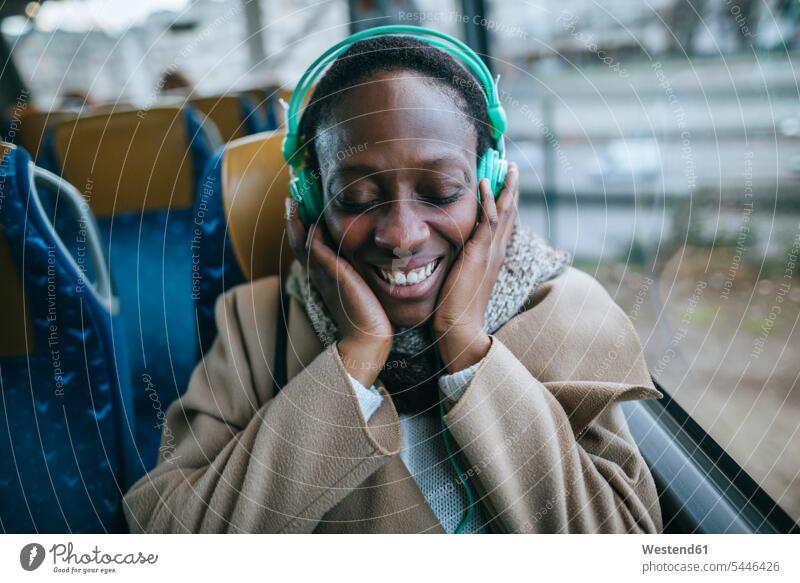 Happy young woman listening music in a bus females women headphones headset portrait portraits Adults grown-ups grownups adult people persons human being humans