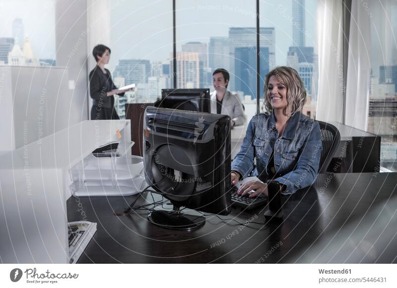 Smiling woman at desk in city office offices office room office rooms working At Work females women smiling smile workplace work place place of work Adults
