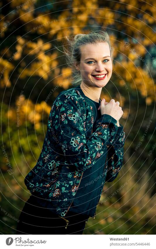 Portrait of smiling young woman in autumnal forest portrait portraits fall females women Adults grown-ups grownups adult people persons human being humans