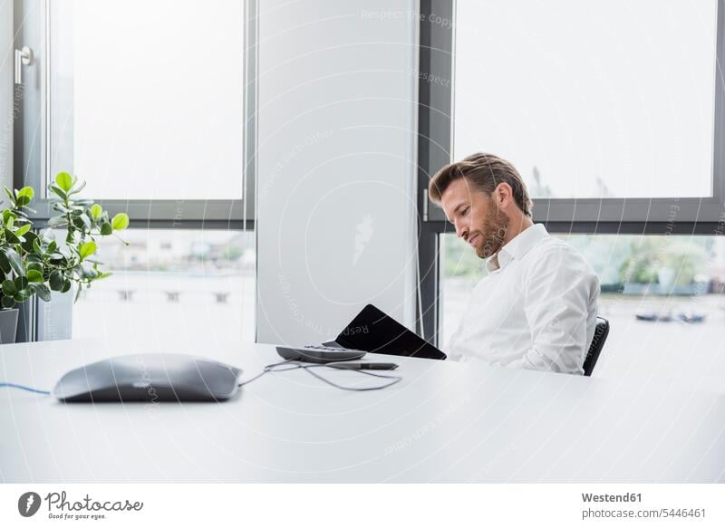 Businessman sitting at desk of his office looking at documents offices office room office rooms Business man Businessmen Business men workplace work place