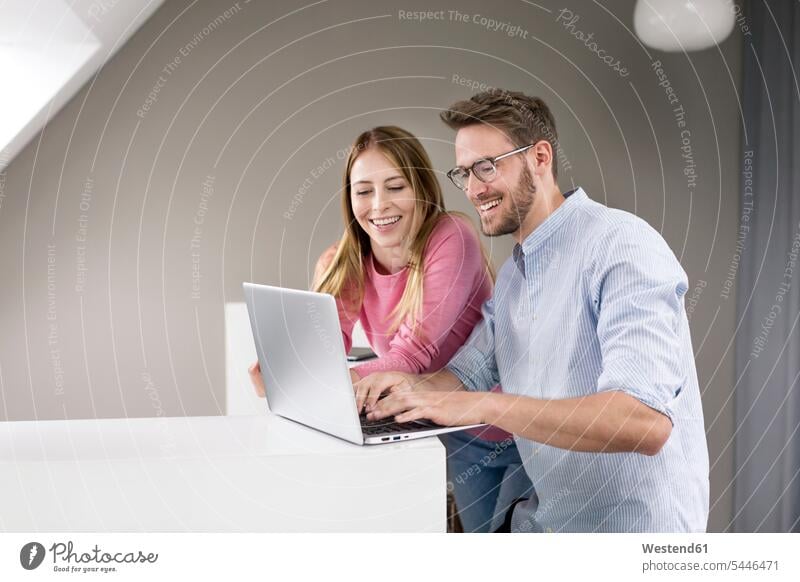 Happy man and woman sharing laptop men males Laptop Computers laptops notebook females women couple twosomes partnership couples colleagues Adults grown-ups