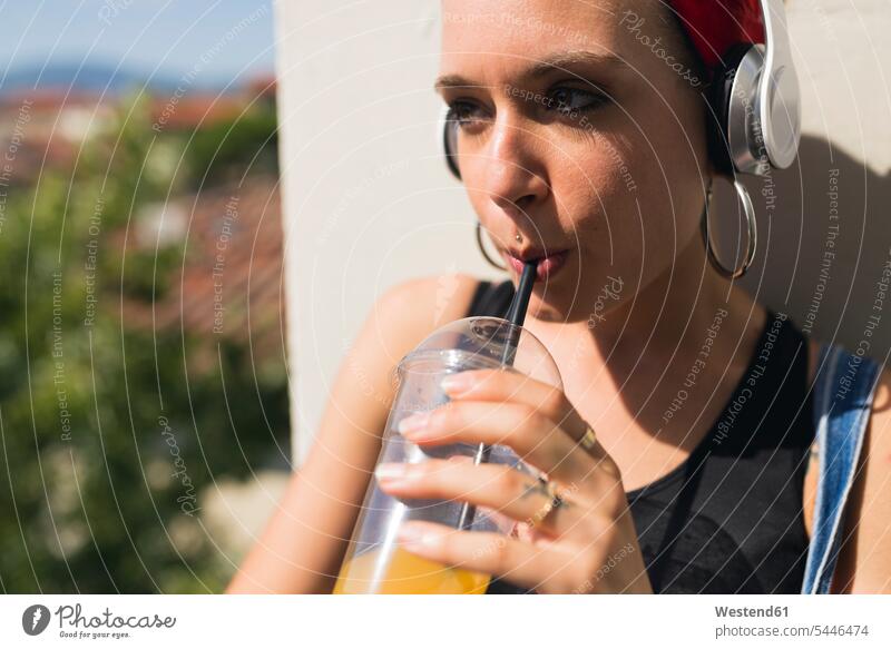 Portrait of young woman with headphones drinking soft drink headset females women Adults grown-ups grownups adult people persons human being humans human beings