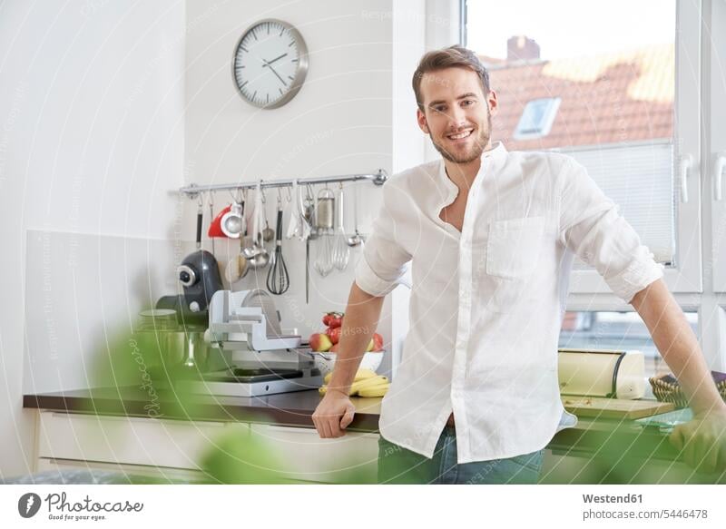 Portrait of smiling young man in kitchen smile men males portrait portraits Adults grown-ups grownups adult people persons human being humans human beings