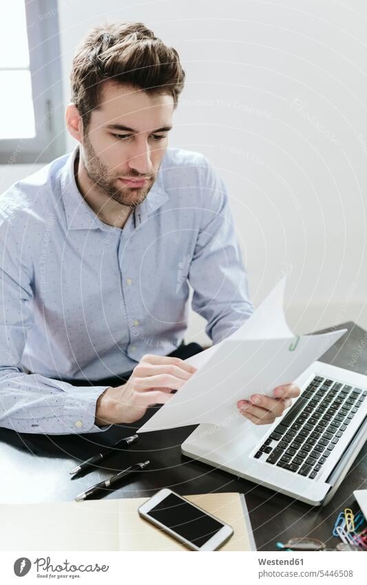 Young businessman working in office, reading documents At Work offices office room office rooms Businessman Business man Businessmen Business men Smartphone
