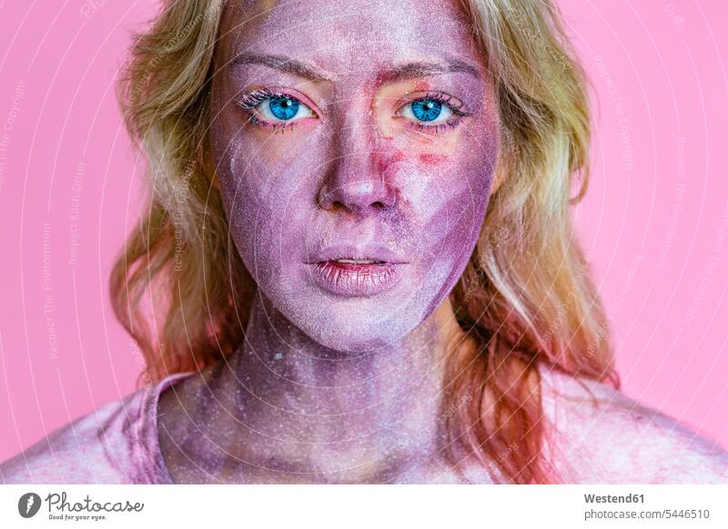 Portrait of young woman with metallic glimmer on her face in front of pink background pigment pigments females women Glimmer Adults grown-ups grownups adult