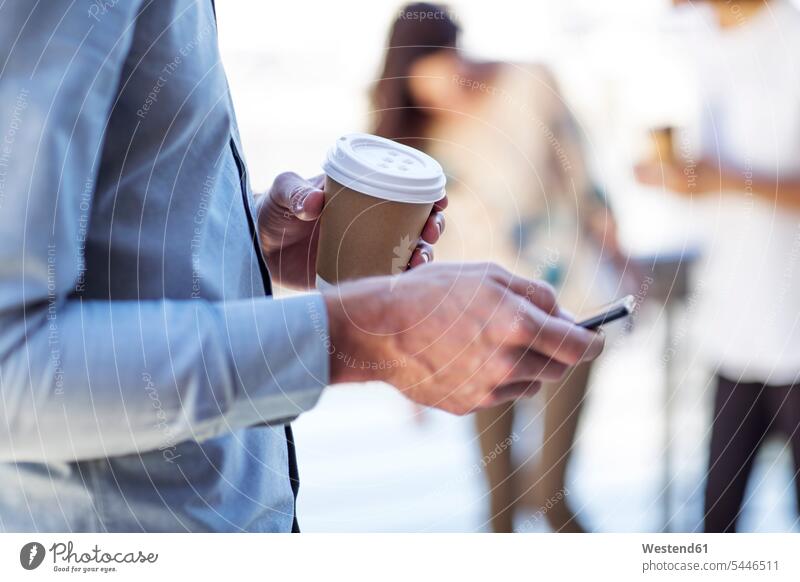 Hand of a man holding cup of coffee, using smartphone texting sending communication mobile phone mobiles mobile phones Cellphone cell phone cell phones