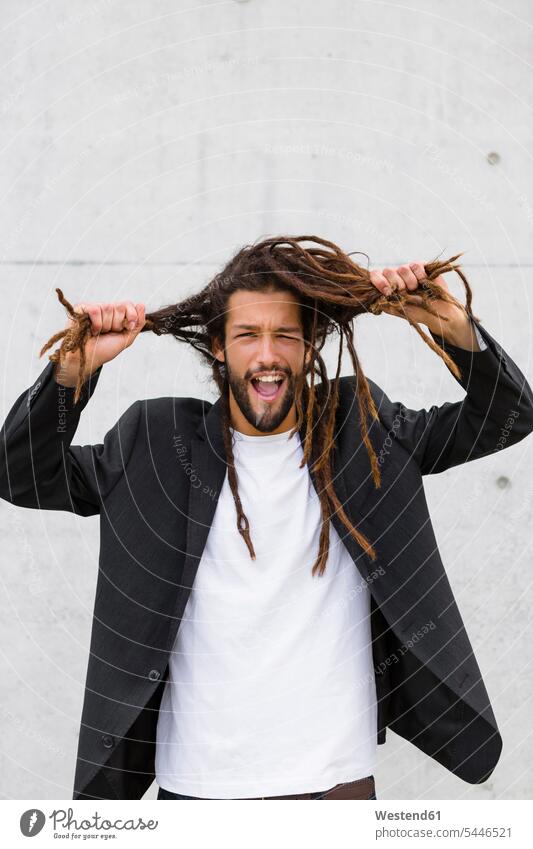 Portrait of young businessman with dreadlocks pulling funny faces portrait portraits men males hairstyle hair-dos hairstyles hairdos people persons human being