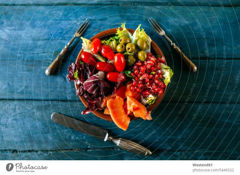 Papaya salad, pomegranate, lettuce, tomato, olives and endive on blue wood vitamines still life still-lifes still lifes pomegranate seed pomegranate seeds
