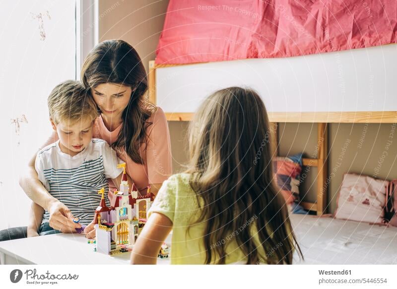 Mother with two children building up toy castle at home playing setting up build up set up mother mommy mothers ma mummy mama family families parents people