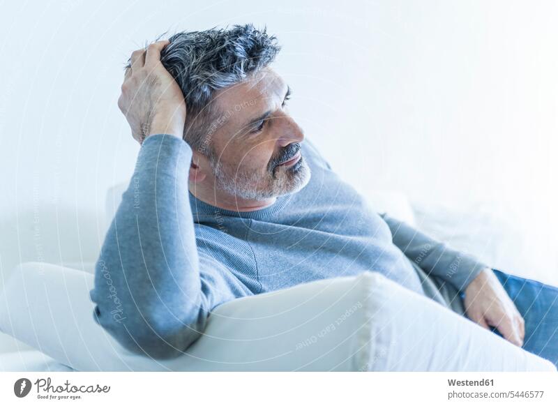 Relaxed mature man at home lying on couch settee sofa sofas couches settees men males laying down lie lying down relaxed relaxation Adults grown-ups grownups