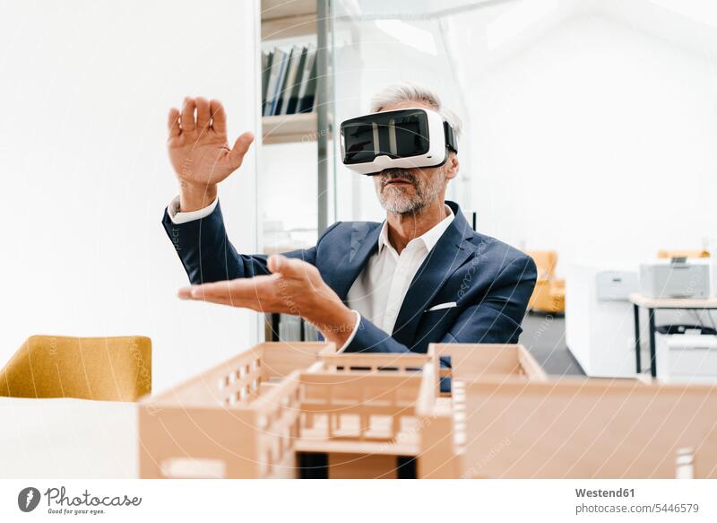 Mature businessman with architectural model in office wearing VR glasses Businessman Business man Businessmen Business men offices office room office rooms