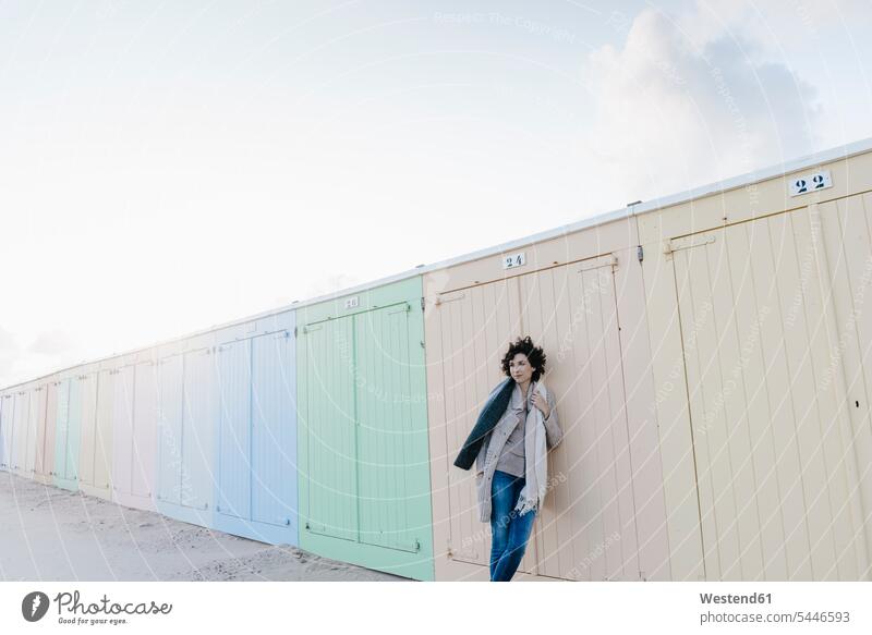 Woman leaning against beach hut standing woman females women beaches Adults grown-ups grownups adult people persons human being humans human beings vacation