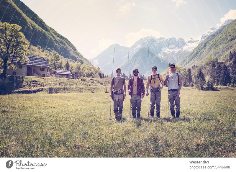 Slovenia, Bovec, four anglers standing on meadow near Soca river friends man men males meadows friendship Adults grown-ups grownups adult people persons