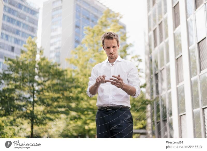 Businessman using portable glass device in front of office building office buildings Tree Trees Business man Businessmen Business men standing built structure