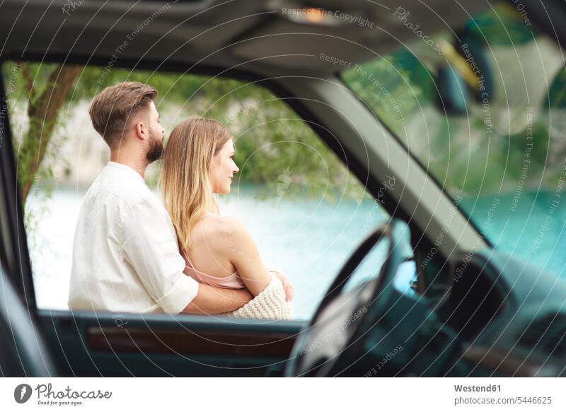 Young couple outside car looking at view twosomes partnership couples Love loving happiness happy relaxed relaxation automobile Auto cars motorcars Automobiles