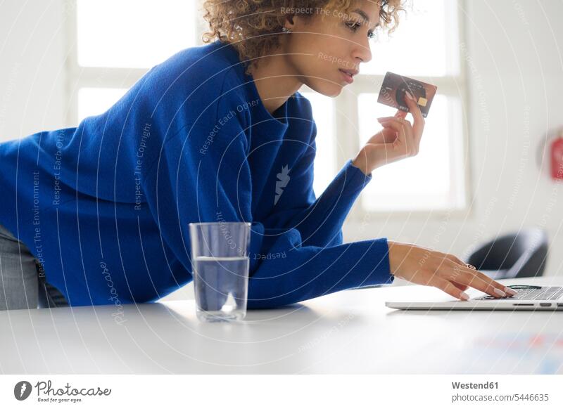 Woman using credit card for paying her online order woman females women use ordering laptop Laptop Computers laptops notebook Table Tables debit card Internet