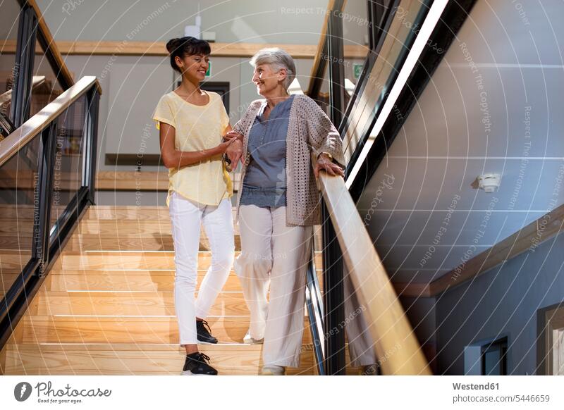 Nurse helping senior woman to walk down the stairs Security Secure climbing stairs assistance assisting Help retirement home nursing home geriatric nurse Care