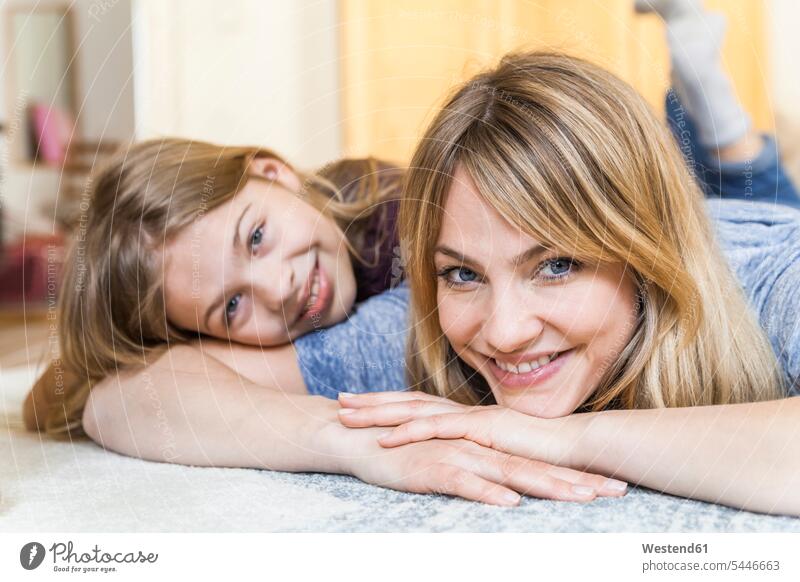 Portrait of smiling blond woman lying on the floor with her daughther portrait portraits mother mommy mothers mummy mama parents family families people persons