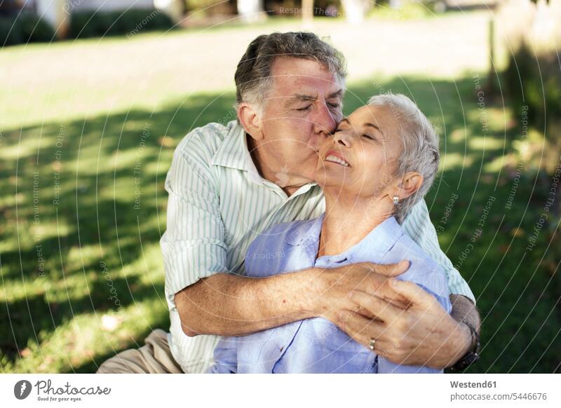 Senior man kissing his wife in garden kisses happiness happy gardens domestic garden couple twosomes partnership couples senior couple elder couples