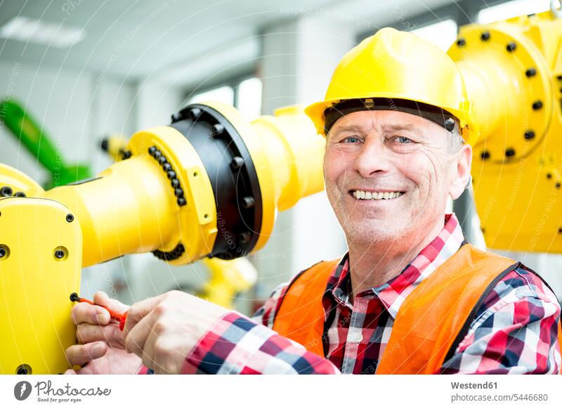 Portrait of smiling technician working on industrial robot factory factories smile At Work industry business business world business life occupation profession