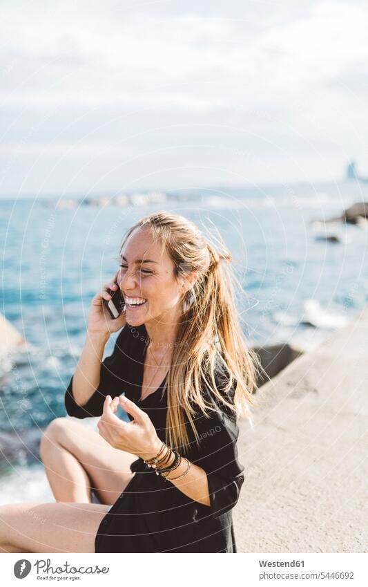 Happy young woman at the seafront on cell phone on the phone call telephoning On The Telephone calling laughing Laughter happiness happy females women
