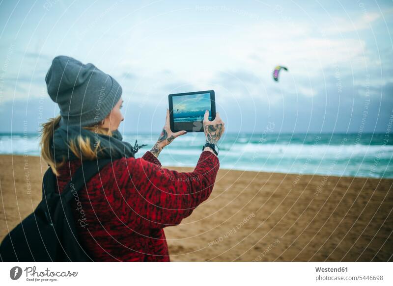 Young woman on the beach in winter taking a cpicture with a tablet photographing beaches females women digitizer Tablet Computer Tablet PC Tablet Computers iPad