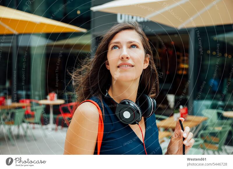 Portrait of smiling young woman with headphones and takeaway drink in the city headset smile portrait portraits females women Adults grown-ups grownups adult