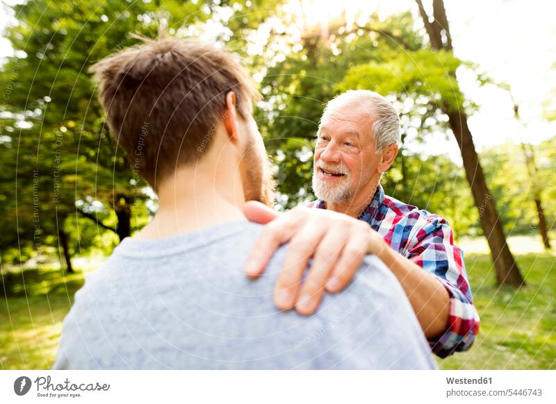 Happy senior father and his adult son in a park fathers daddy dads papa portrait portraits senior men senior man elder man elder men senior citizen parents