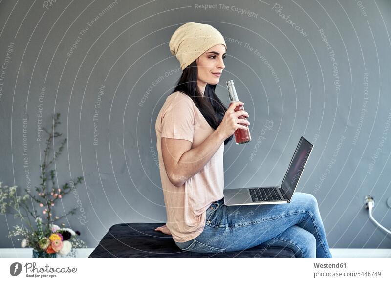 Young woman with laptop holding bottle Laptop Computers laptops notebook sitting Seated Bottle Bottles females women computer computers Adults grown-ups