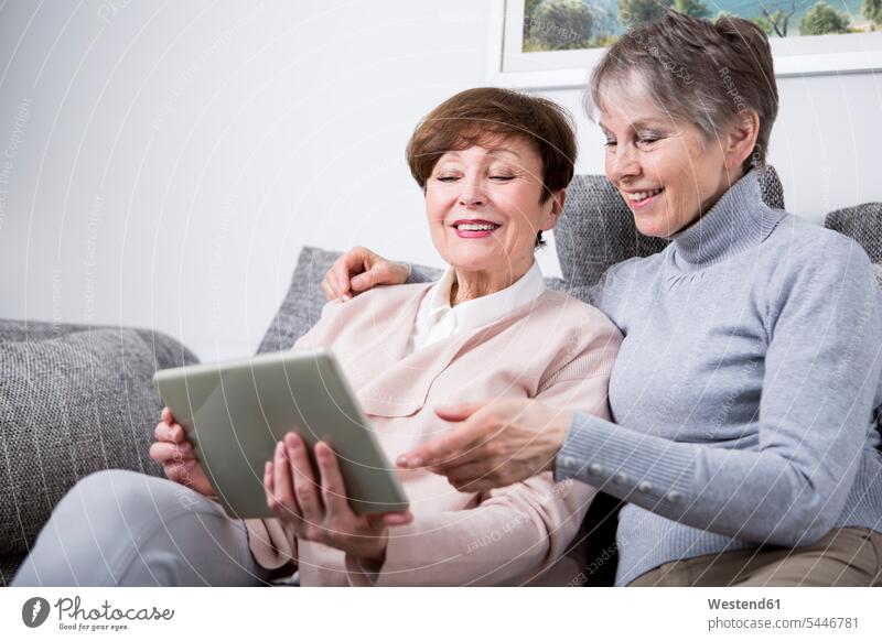 Two senior women sitting on couch, looking at digital tablet female friends together digitizer Tablet Computer Tablet PC Tablet Computers iPad Digital Tablet