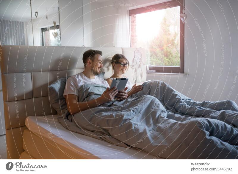 Smiling couple in bed at home with tablets digitizer Tablet Computer Tablet PC Tablet Computers iPad Digital Tablet digital tablets twosomes partnership couples