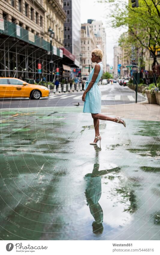 USA, New York, young blonde african-american woman standing on one leg road streets roads Standing On One Leg fashion fashionable African-American Ethnicity
