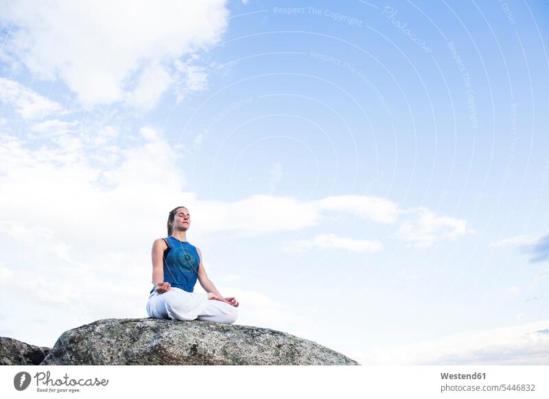 Woman doing yoga sitting on a rock Seated Yoga woman females women exercise exercises Adults grown-ups grownups adult people persons human being humans